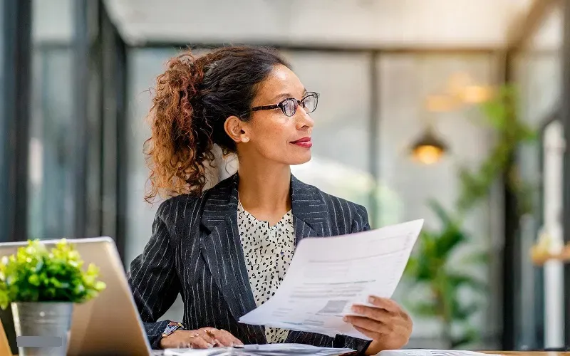 A female professional reviewing documents, illustrating strategic analysis and financial oversight.